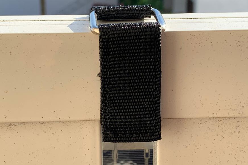 Das leichte Balkonkraftwerk Solarmodul wird mit einem Kreppband im Test befestigt.